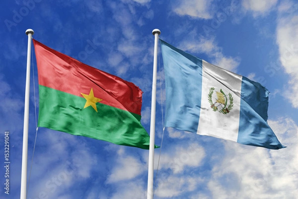 Fototapeta A Burkina Faso and Guatemala flag, a metaphor for global unity, wave together against a blue sky, symbolizing friendship and cultural exchange.