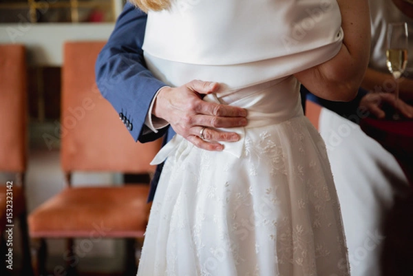 Obraz Close up of a grooms hand hugging the bride in white dress, back view