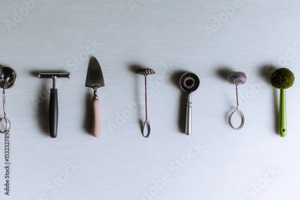 Fototapeta Minimalist arrangement of various kitchen tools, including peeler, spatula, and whisk, showcasing modern and eco friendly aesthetic. This setup emphasizes functionality and style