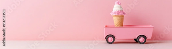 Fototapeta Pink ice cream cone with swirl topping on small pink toy wagon against pastel pink background, playful and sweet