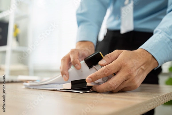 Fototapeta Office Productivity. Businessman organizing documents with a stapler at a modern workspace.