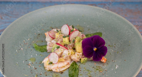 Obraz Delightful ceviche made with fresh dorade and shrimp, complemented by avocado and radish, garnished with an edible flower on a serene green plate.