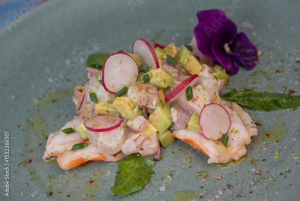 Obraz Delightful ceviche made with fresh dorade and shrimp, complemented by avocado and radish, garnished with an edible flower on a serene green plate.