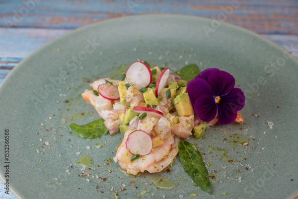 Obraz Delightful ceviche made with fresh dorade and shrimp, complemented by avocado and radish, garnished with an edible flower on a serene green plate.