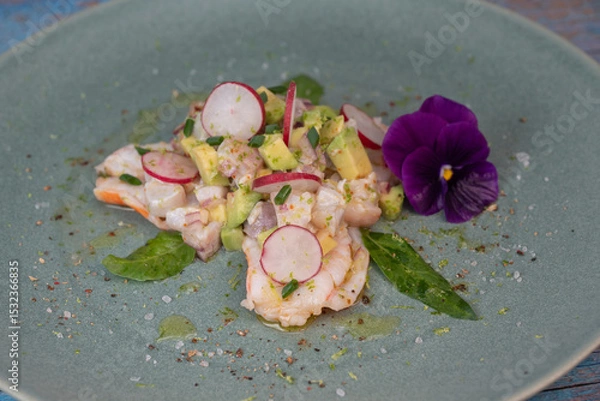 Obraz Delightful ceviche made with fresh dorade and shrimp, complemented by avocado and radish, garnished with an edible flower on a serene green plate.