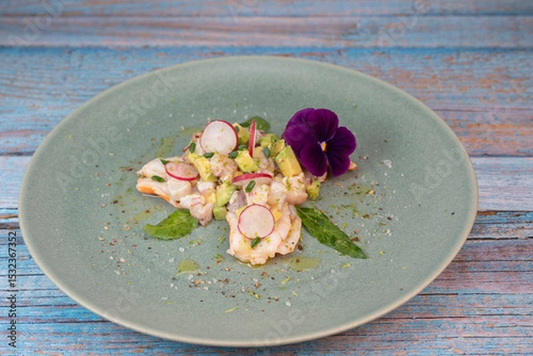 Obraz Delightful ceviche made with fresh dorade and shrimp, complemented by avocado and radish, garnished with an edible flower on a serene green plate.