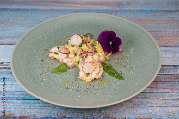 Obraz Delightful ceviche made with fresh dorade and shrimp, complemented by avocado and radish, garnished with an edible flower on a serene green plate.