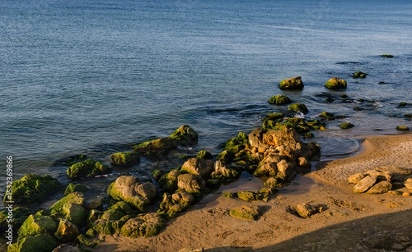 Fototapeta seashore with rocks among which water flows with open sea
