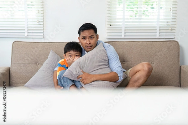 Fototapeta Family Bonding and Fun. Father and son enjoying a thrilling movie moment on the couch.