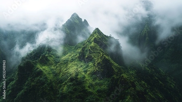 Fototapeta Misty green mountain peaks rise sharply through dense fog, showcasing lush vegetation and rugged terrain in a serene, atmospheric landscape.