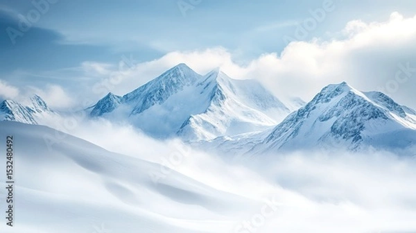 Fototapeta Snow-covered mountain peaks under a bright blue sky with soft clouds, showcasing a pristine winter landscape.