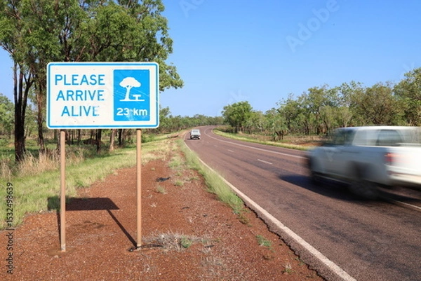Fototapeta Road sign, please arrive alive. Road safety. Roadside rest area sign, 23km ahead. Fast, speeding car, motion blur. Australia Outback, rural area. Accident, incident, death toll, injuries, statistics