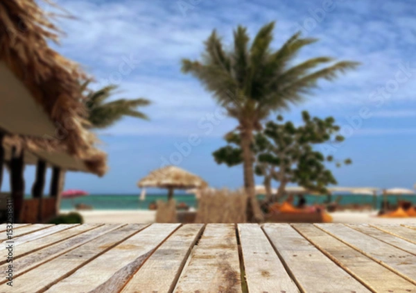 Fototapeta Wooden table top on the beach or sea.Party on the beach  sunshine time concept.For montage product display or design key visual layout.View of copy space.