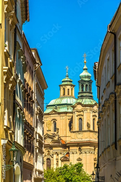 Fototapeta A view down an ornate side street towards some of the many spires in central Prague in springtime