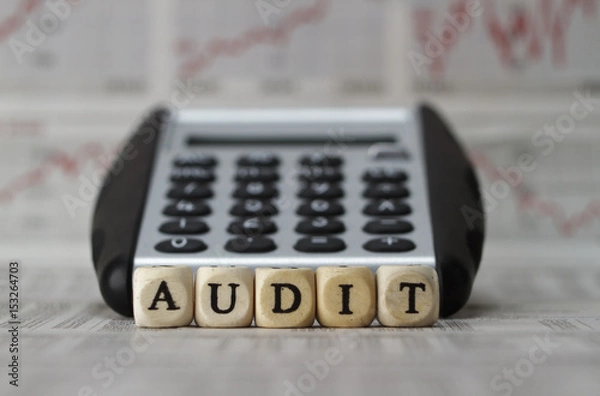 Obraz Audit word built with letter cubes on newspaper background