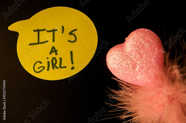 Fototapeta Photograph of a Yellow Emoji with “It’s a Girl” Text on Black Background