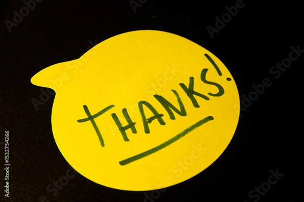 Fototapeta Photograph of a yellow emoji on a black background with this word "Thanks" written inside.