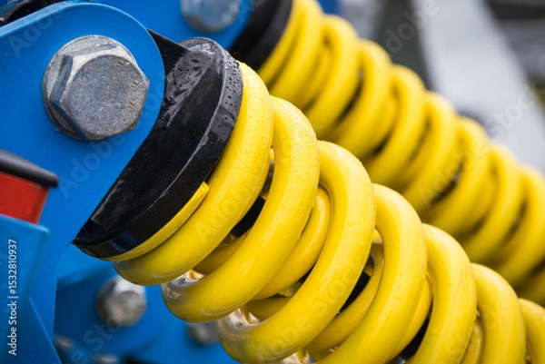 Obraz Steel yellow spring as part of blue agricultural machine. Technology
