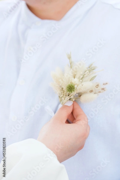 Obraz Man in white shirt receives a flower boutonniere from a hand