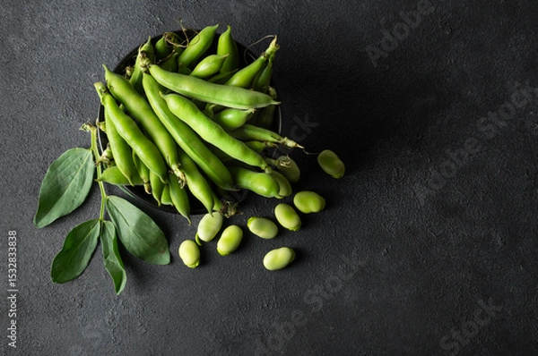 Fototapeta Fresh broad beans with pod in bowl on dark rustic background, healthy food