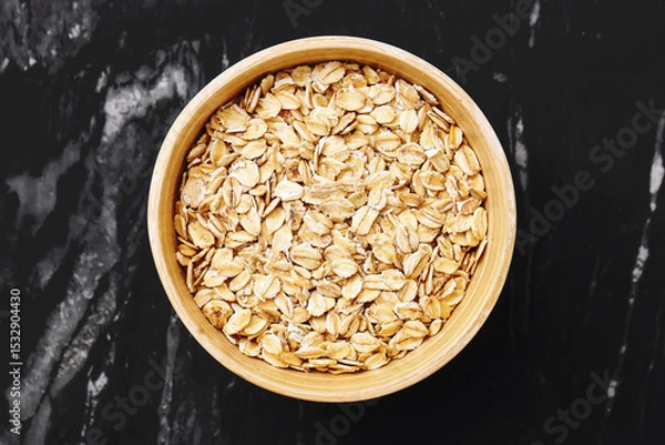 Fototapeta Raw oats in bamboo bowl. Healthy organic grain for breakfast. Top view on marble table. Rustic natural background. Vegan dietary fiber source. Clean eating concept. Natural whole grain.