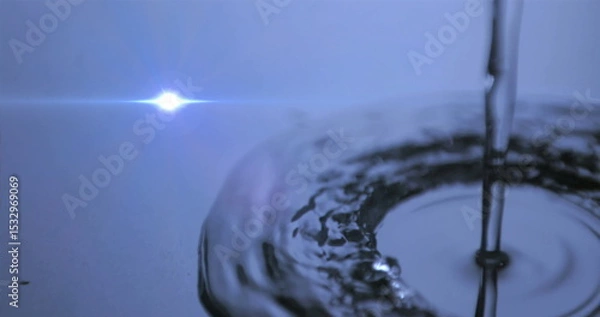 Obraz Pouring water stream creating ripples on reflective surface in studio, with lens flare, copy space