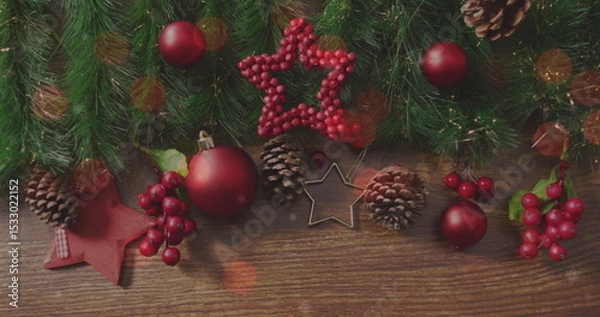 Fototapeta Displaying Christmas decor on wood table with red baubles, pine branches and star cookie cutter
