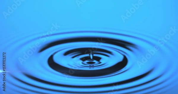 Fototapeta Capturing water droplet creating concentric ripples on reflective water surface in studio