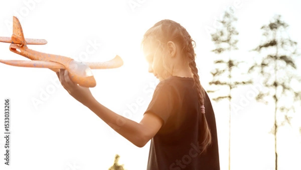 Fototapeta Playful girl kid run with airplane on background amazing summer warm sunset. Dream freedom concept. Child runs on field holding in hands toy aircraft