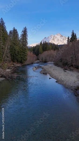 Obraz A scenic view of a river flowing towards a snow capped mountain under a clear blue sky in daytime