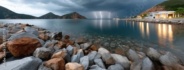 Fototapeta Lightning flashes over seaside rocks, adding to the night's mystery with dark clouds and distant mountains