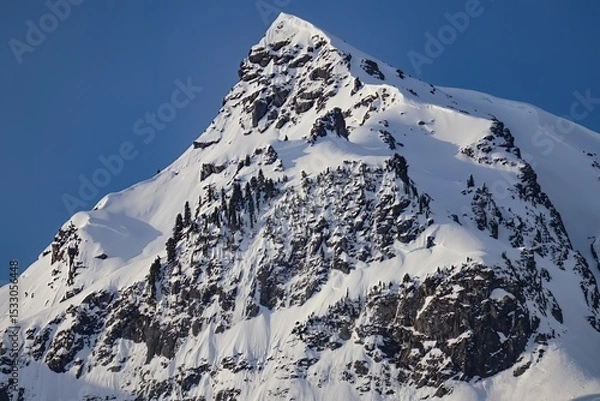 Obraz A view of a snow covered mountain peak against a clear blue sky on a bright sunny day in winter