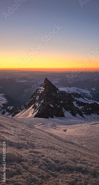 Obraz Snowy mountain peak at sunset with orange and blue sky and distant mountain range view from above
