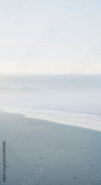 Obraz Serene Foggy Beach with Gentle Waves and Footprints
