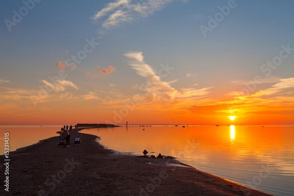 Fototapeta Colorful sunset over sand coast of the sea. People enjoying dawn