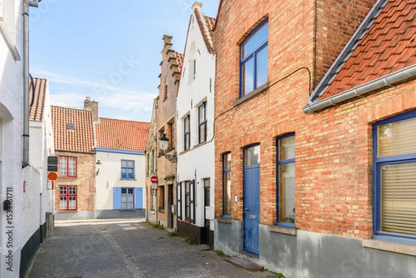 Fototapeta Cobbled street lined with traditional brick row houses in a historic city centre on a sunny summer day