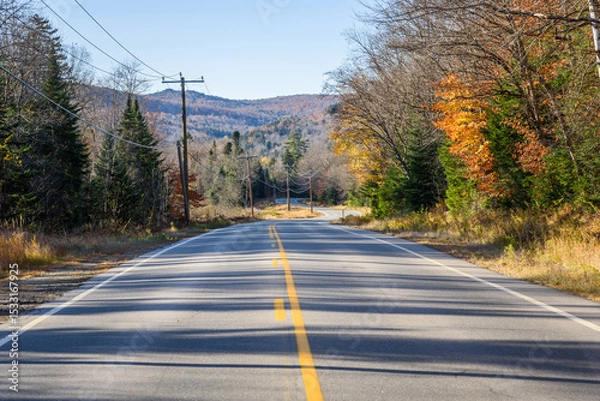 Fototapeta Empty winding road through a mountain valley at sunset in autumn