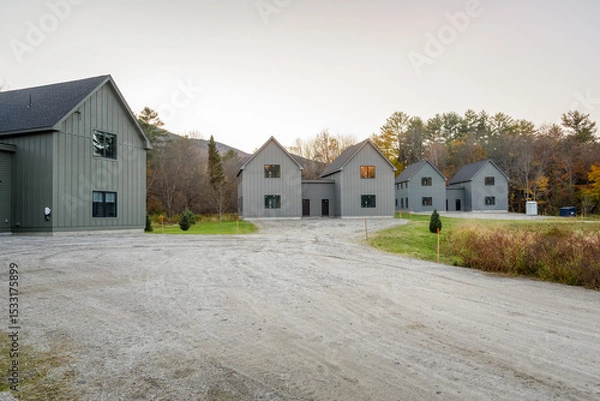 Fototapeta Semi-detached houses under construction in a housing development surrounded by woodland in the mountains at sunset in autumn