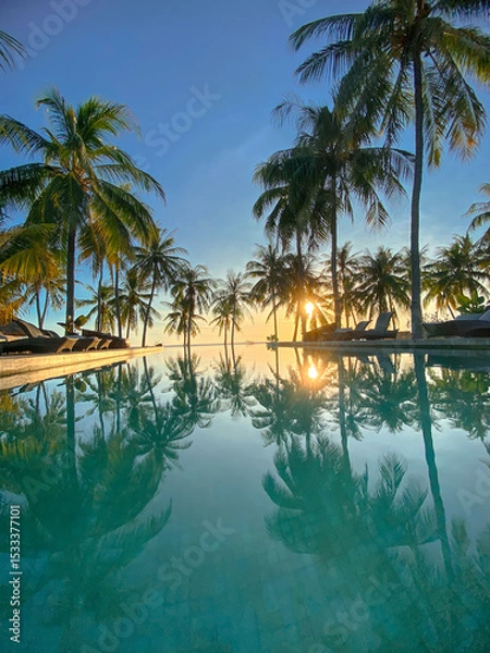 Fototapeta Tropical sunset view at a resort pool with palm tree reflections.