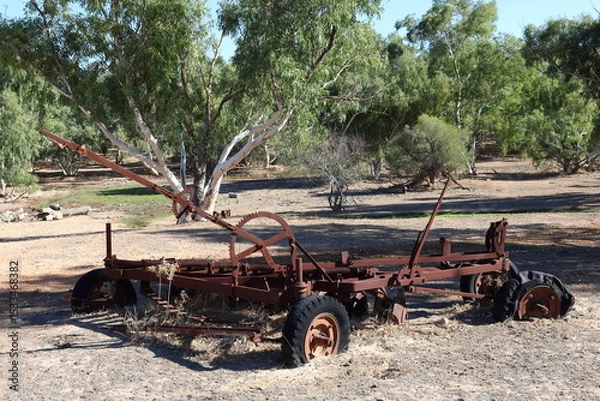 Fototapeta Vintage, old, rusty agriculture, farming equipment abandoned in remote Australian Outback, amongst Eucalyptus trees. History, nostalgia, scrap, collection, travel and tourism