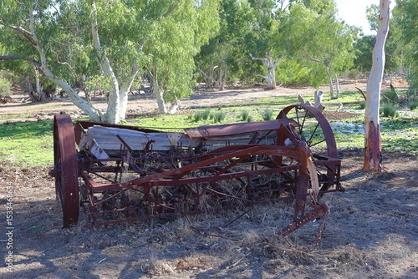 Fototapeta Vintage, old, rusty agriculture, farming equipment abandoned in remote Australian Outback, amongst Eucalyptus trees. History, nostalgia, scrap, collection, travel and tourism