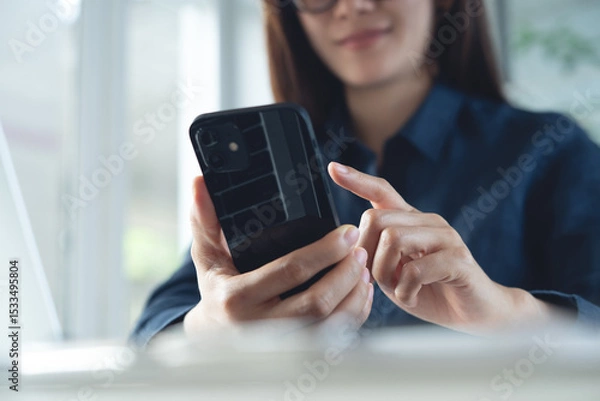 Obraz Happy young asian business woman using mobile phone for online shopping and digital banking via mobile app with laptop computer on office table. 