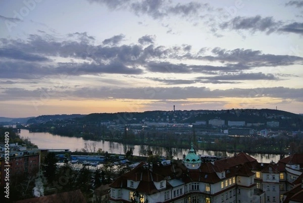 Fototapeta Rooftop view of a picturesque cityscape with flowing river and distant hills at dusk, illuminated skyline during sunset, urban landscape and travel destination scenic beauty