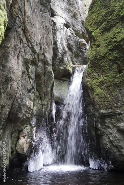 Fototapeta Majestic waterfall cascading over moss-covered rocks in a tranquil forest setting, serene natural landscape, refreshing outdoor travel experience