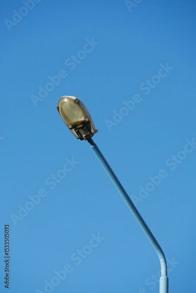 Fototapeta Street lamp post isolated against clear blue sky, minimalist urban lighting design, featureless background for architecture and city infrastructure concept