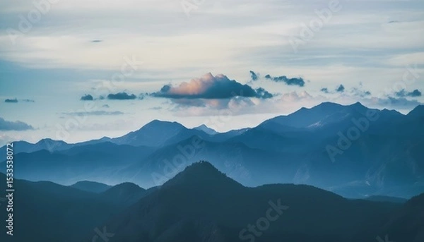 Obraz A landscape of mountains with a cloudy sky, the mountains are blue and the sky is blue.