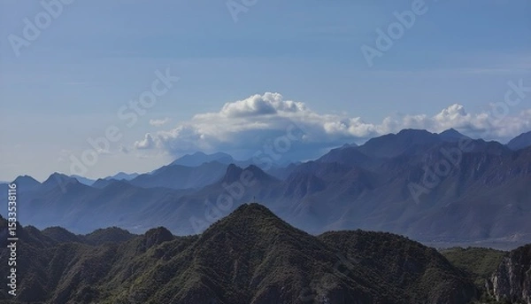 Obraz A landscape of mountains with a cloudy sky, the mountains are blue and the sky is blue.