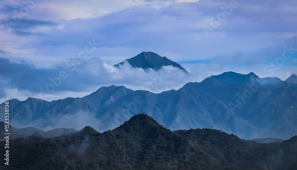 Obraz A landscape of mountains with a cloudy sky, the mountains are blue and the sky is blue.