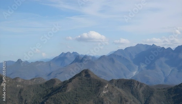Obraz A landscape of mountains with a cloudy sky, the mountains are blue and the sky is blue.