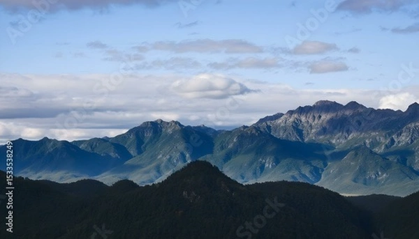 Obraz A landscape of mountains with a cloudy sky, the mountains are blue and the sky is blue.